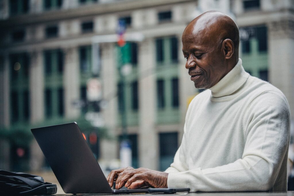 Man using a laptop with a city building in the background