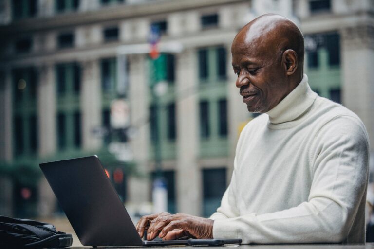 Man using a laptop with a city building in the background