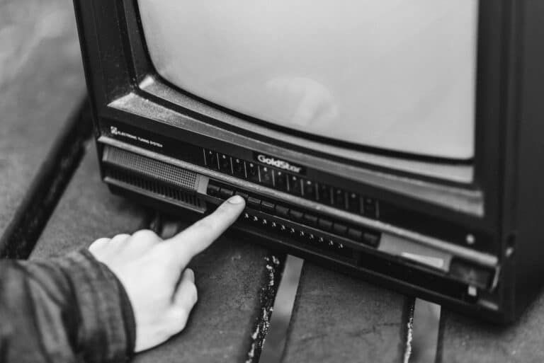 Finger pushing buttons on an old television set